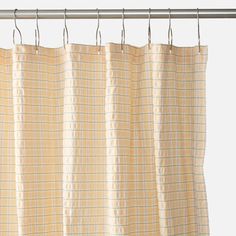 a curtain hanging on a metal rod in front of a white wall with a yellow checkered pattern