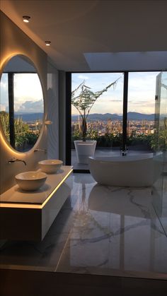 a bathroom with two sinks and a bathtub in front of large windows overlooking the city