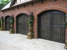 a brick building with three wooden garage doors