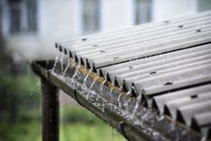 the rain is falling down on an outdoor bench