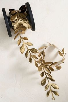 a metal object with leaves on it hanging from the wall next to a pair of scissors