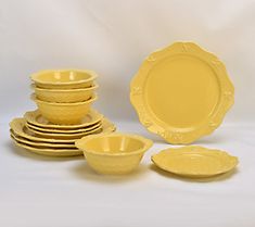 a yellow dinnerware set on a white background with plates and bowls in the foreground