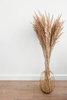 some dry grass in a vase on the floor