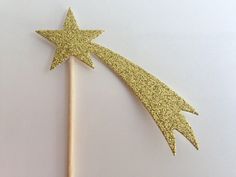 a gold glittered star on top of a wooden stick