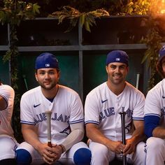 three baseball players pose for a photo in front of the dugout with their bats