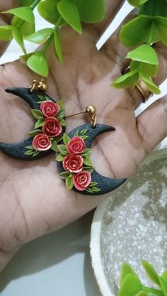 a person's hand holding some kind of brooch with flowers on it,