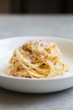 a white plate topped with pasta covered in parmesan cheese