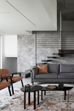 a living room filled with furniture next to a stair case on the side of a wall