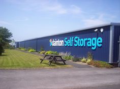 a blue storage building with a picnic table in front