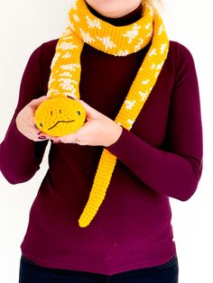 a woman wearing a yellow scarf holding a smiley face knitted hat and scarves