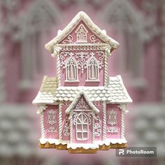 a pink and white doll house on display in front of a wall with ornate windows