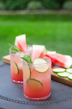 two glasses filled with watermelon and cucumber on top of a table