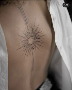 the back of a woman's stomach with a sun tattoo on her left side