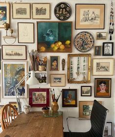 a wooden table sitting in front of a wall filled with pictures and art on it