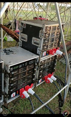 an old metal box sitting on top of a field next to wires and plugs