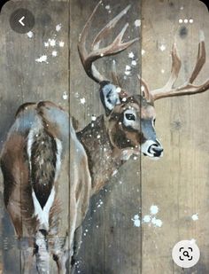 an image of a deer painted on wood planks with snow falling off it's antlers