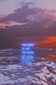 the best is yet to come written in neon blue on water with clouds and sunset