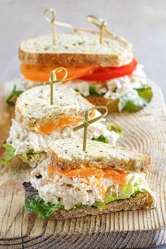 there is a sandwich that has been cut in half on a cutting board with toothpicks