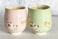 two ceramic cups with cats painted on them