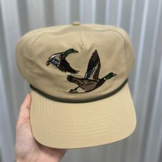 Made for the hunting enthusiast, our Ensenada Rope Hat - Wildlife - Ducks is crafted from 100% ripstop polyester and features an adjustable snap closure for the perfect fit. This hat is lightweight and durable, making it the perfect accessory to your morning duck blind adventures. 100% Ripstop Polyester Custom Pointer Design Adjustable Snap Closure Unisex Sizing Adjustable Flat Bill Fitted Hat For Outdoor, Adjustable Khaki Hat For Hiking, Adjustable Khaki Hiking Hats, Adjustable Flat Bill Hat In Khaki, Adjustable Khaki Flat Bill Hat, Casual Hunting Hat With Flat Brim, Casual Adjustable Hat Bands For Hunting, Khaki Snapback Trucker Hat For Outdoor Activities, Outdoor Adjustable Fit Snapback Hat