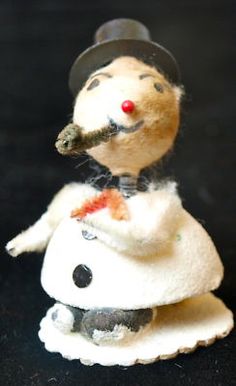 a toy mouse wearing a hat and holding a pipe in its mouth, sitting on a black surface