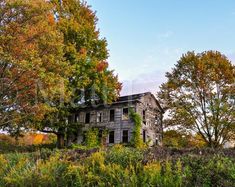 an old abandoned house surrounded by trees in the fall