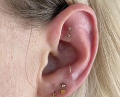 a close up of a person's ear with gold piercings