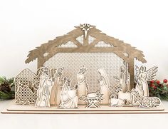 the nativity scene is made out of wood and laser - cut paper, with christmas decorations around it