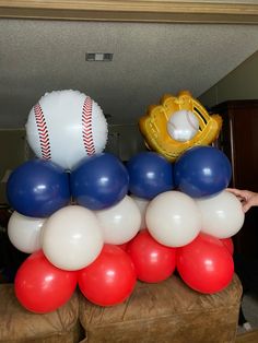 a bunch of balloons that are sitting on top of a couch with baseballs and mitts