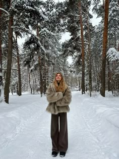 a woman is standing in the snow with her arms wrapped around her waist and wearing fur