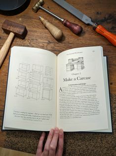 an open book sitting on top of a wooden table next to other tools and equipment