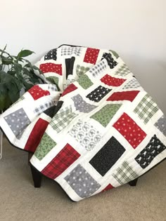 a quilted blanket sitting on top of a footstool next to a potted plant