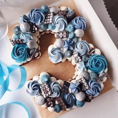 a decorated number made out of cupcakes on top of a box with blue ribbons