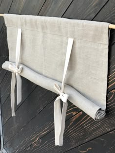 the back of a curtain hanging on a wooden wall with white ribbon tied around it