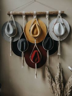 four hats hanging on a wall with string and hooks attached to it, one hat has a tear in the middle