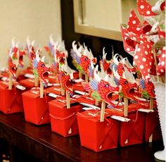 there are many red and white boxes on the table with streamers in each one