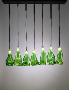 five green glass bottles hanging from black cords