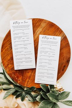 two wedding program cards sitting on top of a wooden plate