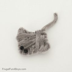 an animal made out of yarn and buttons sitting on top of snow covered ground with white background