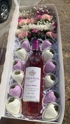 a bottle of wine sitting in a box filled with chocolate covered strawberries and flowers