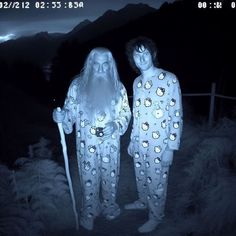 two people dressed as santa claus standing next to each other in the woods at night