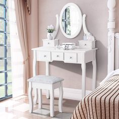 a white dressing table with a mirror and stool in a pink walled room next to a window