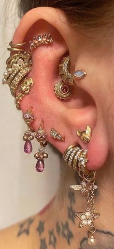 a woman with piercings on her ear is wearing some gold and pink jewelry set