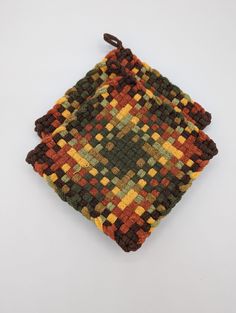 a small square made out of multicolored knitted material on a white surface