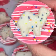 a person is holding a cookie with icing and sprinkles on it