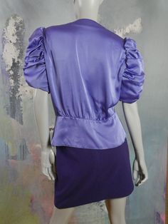 This 1980s violet purple satin blouse has a V crossover neckline edged with three pleats on each side, a fitted waistline defined with a seam, and a three-button material-covered button closure on the peplum-style waistband. The top has elegant gathered short puffed sleeves. Bust = 40 inches (101.6cm) Shoulders = 16.5 inches (41.91cm) Waist = 33 inches (83.82cm) Hips = 42 inches (106.68cm) Sleeve Length = 12 inches (30.48cm) Top Length = 23.5 inches (59.69cm) Size: 12 US, 16 UK Material: Polyest Peplum Styles, Purple Satin, Check Dress, Satin Blouse, Polyester Satin, European Vintage, 1960s Fashion, Quality Clothing, Wool Blend