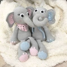 two crocheted stuffed elephants sitting on top of a white fluffy blanket in the shape of an elephant