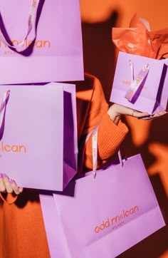 a woman holding three purple shopping bags with the word, old michigan on them and an orange background