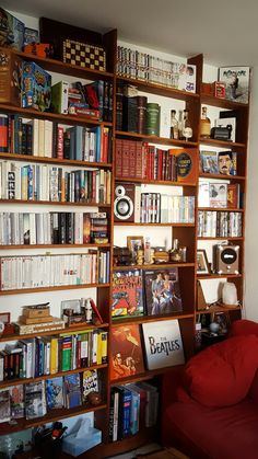 a red couch sitting in front of a book shelf filled with books