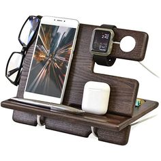 a cell phone and glasses are sitting on a wooden stand with two charging devices attached to it